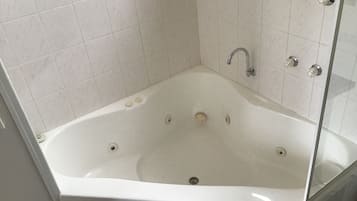 Una bañera blanca independiente con ducha y mandos.