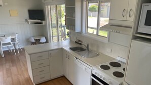 Una cocina compacta con lavavajillas, estufa y fregadero.