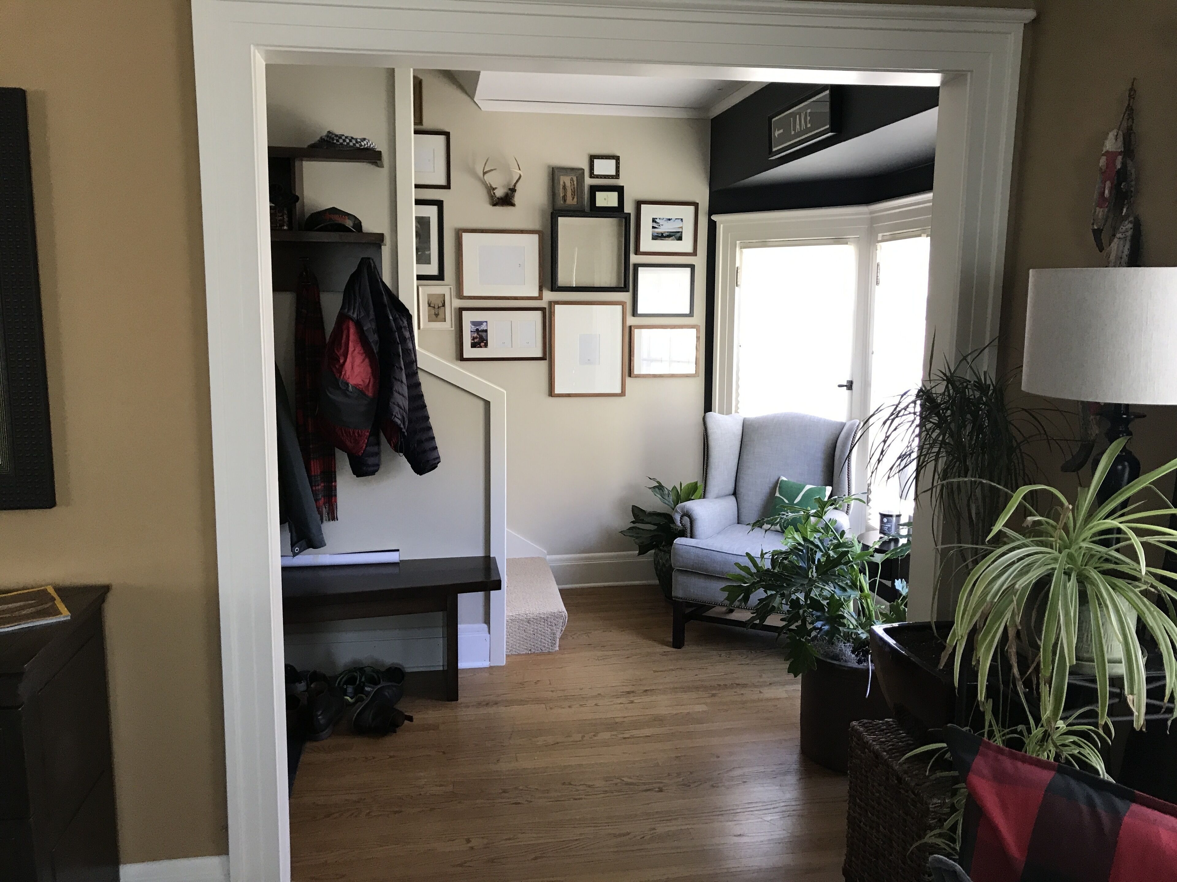 A living room with a staircase, a grey armchair, and a potted plant.
