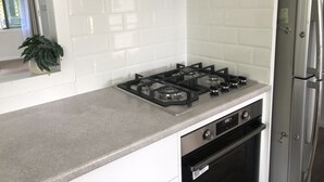 Una cocina con estufa a gas, horno y refrigerador de acero inoxidable.