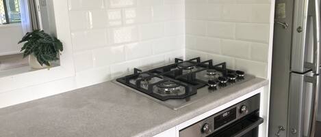 A kitchen with a gas stove, oven, and a stainless steel refrigerator.
