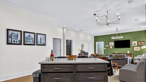 A modern kitchen with a central island, a dining area with a sofa, and a green accent wall. - Historic Levy Penthouse Downtown Louisville (Louisville)