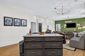 A modern kitchen with a central island, a dining area with a sofa, and a green accent wall. - Historic Levy Penthouse Downtown Louisville (Louisville)