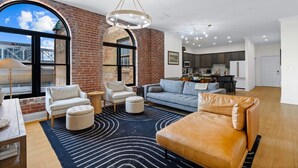 A spacious living area with a large window, a fireplace, and a kitchen in the background. - Historic Levy Penthouse Downtown Louisville (Louisville)