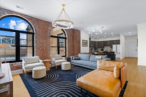 A spacious living area with a large window, a fireplace, and a kitchen in the background. - Historic Levy Penthouse Downtown Louisville (Louisville)
