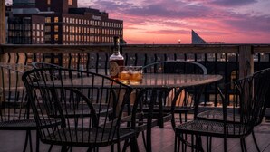 A rooftop terrace with a table set for two, a bottle of liquor, and glasses. - Historic Levy Penthouse Downtown Louisville (Louisville)