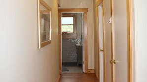 Un estrecho pasillo con puertas de madera y un cuadro en la pared.