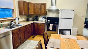 Una cocina compacta con armarios de madera, un lavamanos de acero inoxidable, una estufa y un refrigerador.