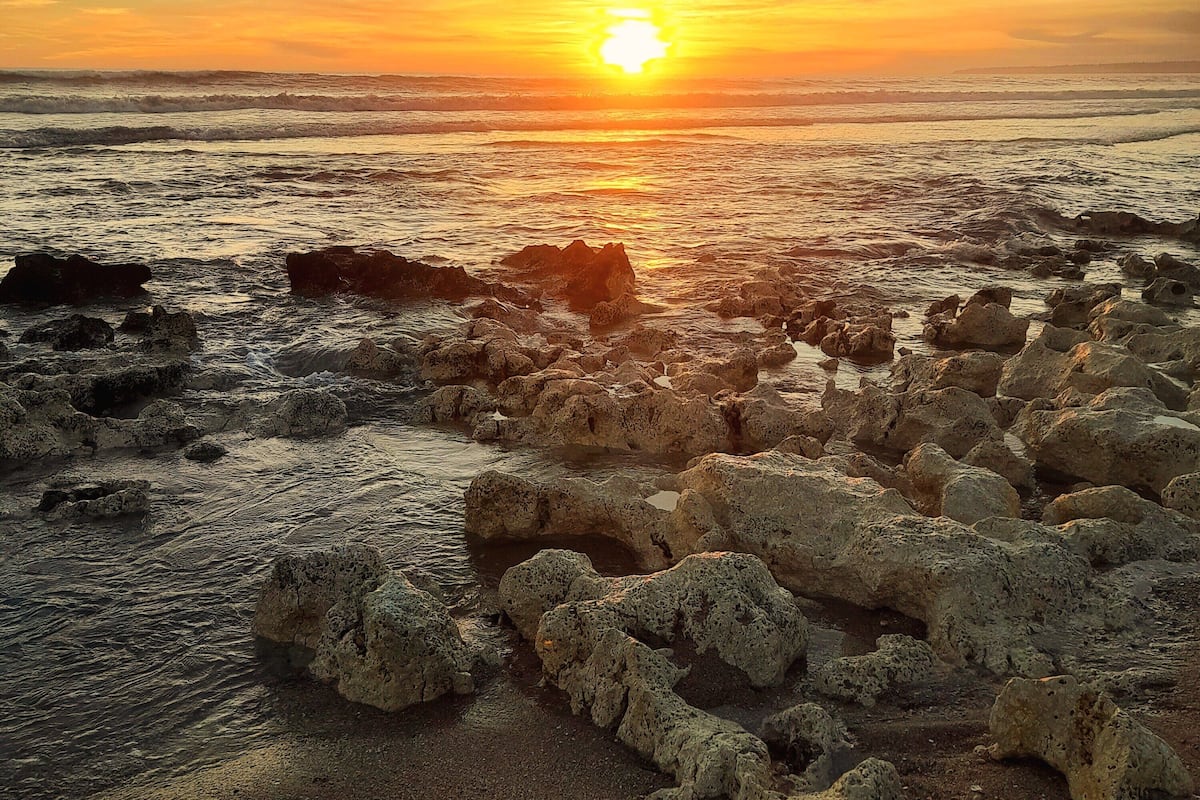 Un rivage rocheux, avec des vagues au coucher du soleil.