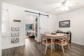 A dining area with a wooden table and chairs, a ceiling fan, and a view of a room with a sliding door.