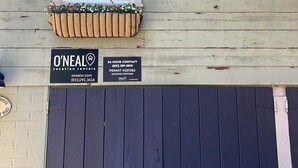 Et hus med et vindue, en træplantekasse med blomster, et skilt for O'Neal vacation rentals, og en mørkeblå garageport.
