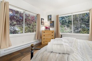 A bedroom with a bed, a dresser, and a window with curtains.