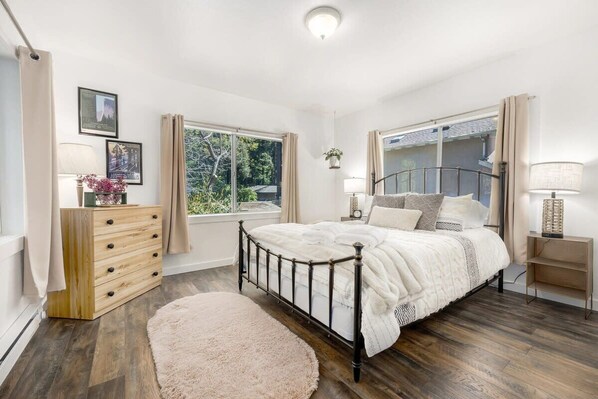 A bedroom with a bed, a dresser, a window, and a lamp.