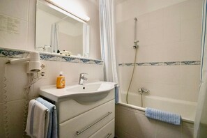 A bathroom with a sink, mirror, shower, and towel rack.