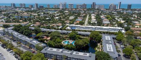 A large hotel complex with multiple buildings, a central pool area, and a view of the ocean.