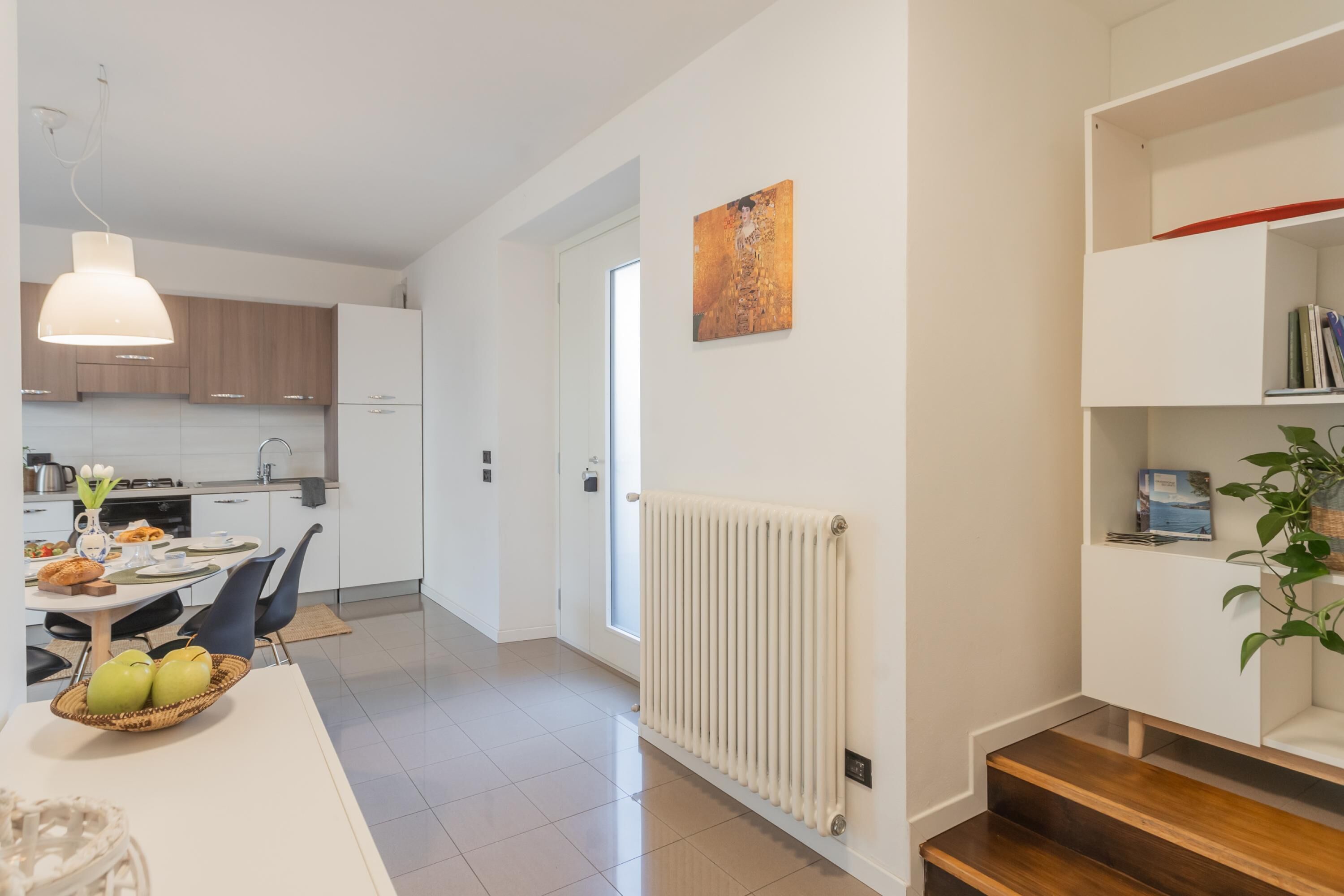 A modern kitchen with white cabinets, a dining area with a white table, and a staircase leading to a landing.