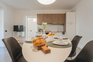 Una cucina moderna con mobili in legno, un tavolo da pranzo apparecchiato con piatti, tazze e una pagnotta.