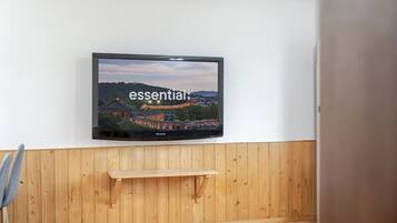 Ein Flachbildfernseher an einer weißen Wand, unterhalb davon eine Holzvertäfelung.