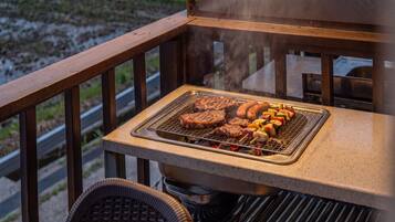 Una parrilla con filetes, salchichas y verduras en un balcón.