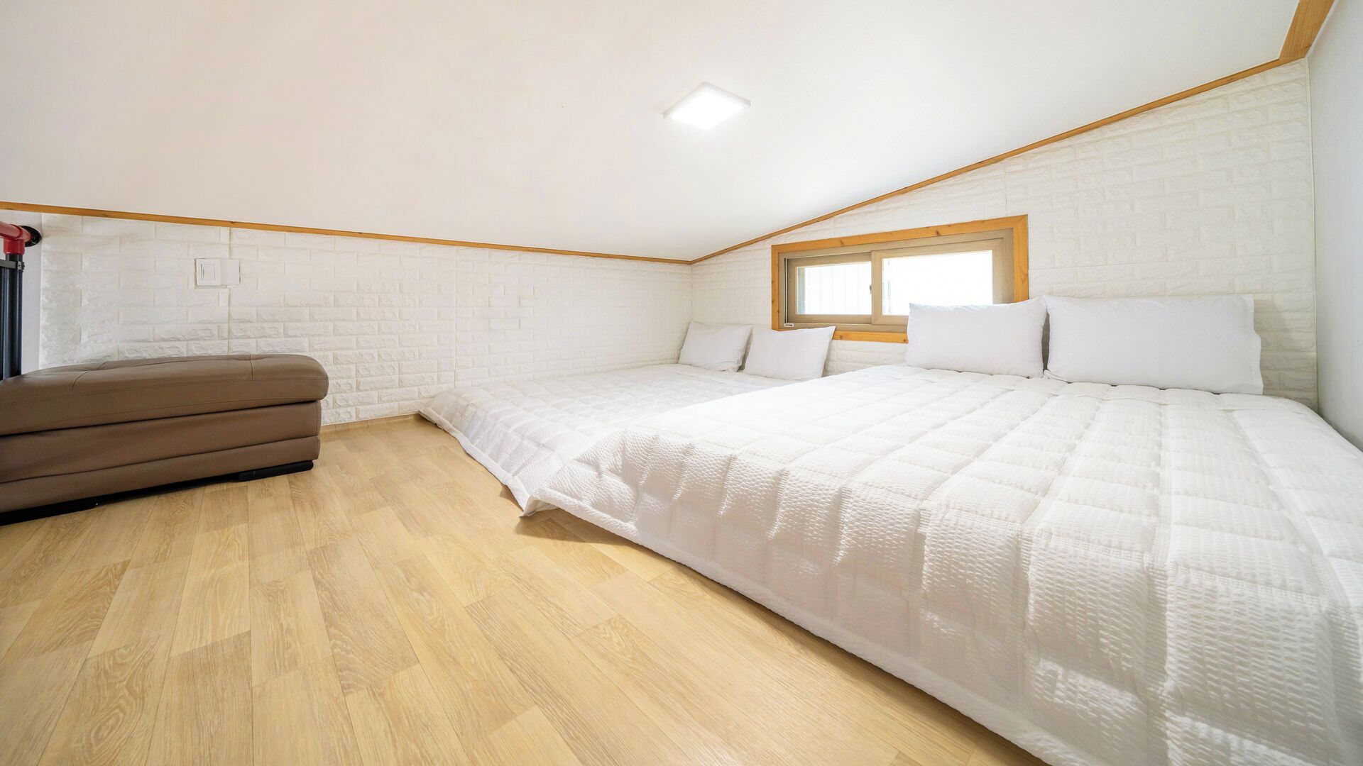 A bedroom with a loft bed, a sofa, and a window.
