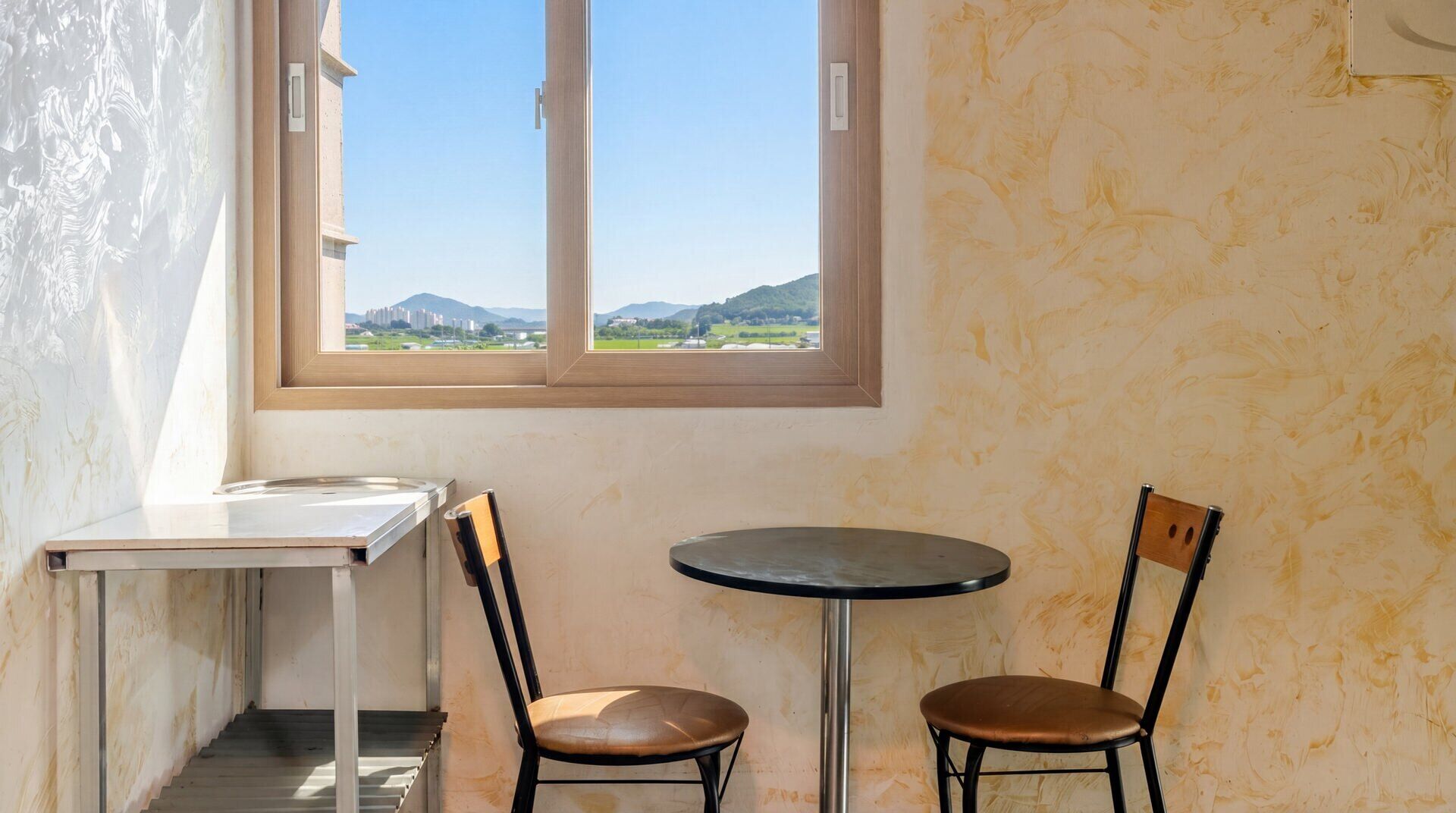 A small room with a window, a table, and two chairs.