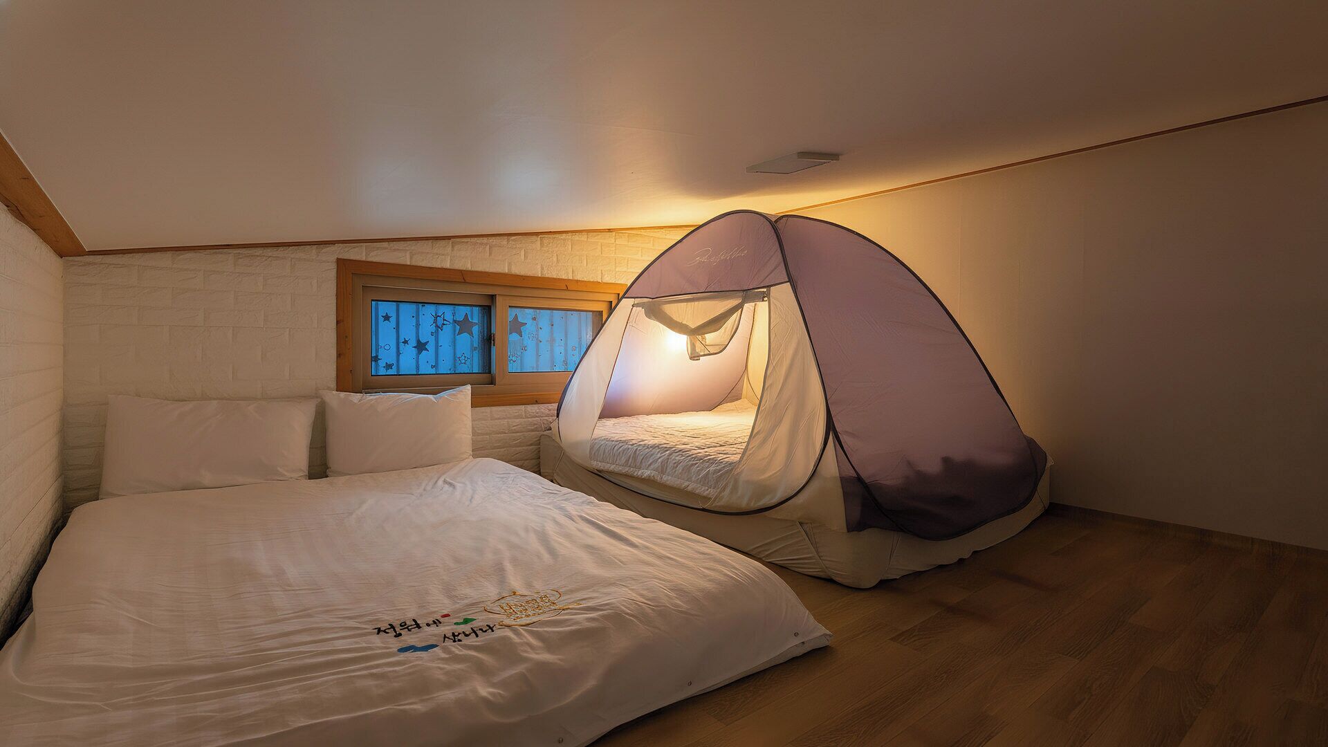 A bedroom with a bed, a window, and a tent-like structure.