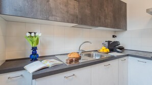 A modern kitchen with a dark countertop, white cabinets, a stainless steel sink, and a coffee maker. - Ponente Balcony in Gravedona (Gravedona)