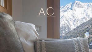 Una cama con un almohadón mullido y una manta tejida, una ventana con vistas a la montaña, y un letrero que dice "AC Property Manager".