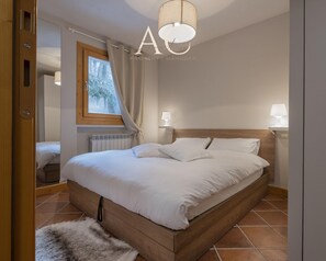 A bedroom with a wooden bed, white bedding, a window with curtains, a radiator, and a fluffy rug. - Instaview in Pontagna (Temu)