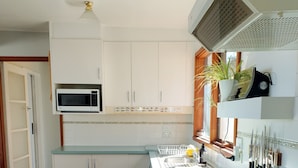 A kitchen with white cabinets, a microwave, a stove, and a sink.