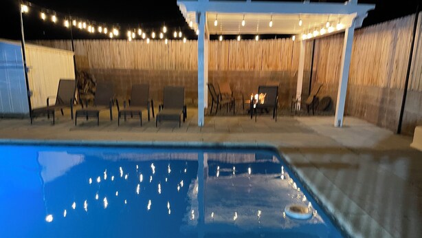 A swimming pool with chairs and a pergola with string lights. - Awesome Pool House in the Kern River Valley (Wofford Heights)