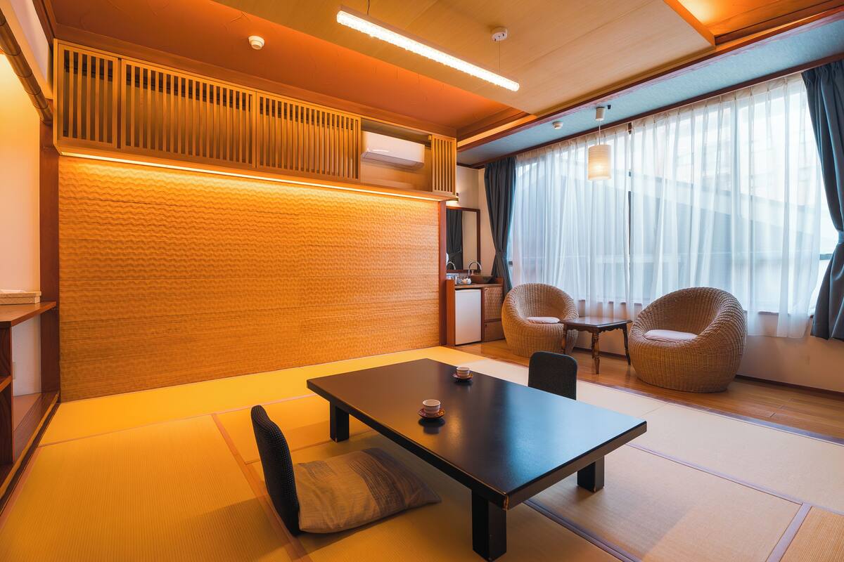 A traditional Japanese-style room with tatami flooring, a low table, and two cushioned chairs.