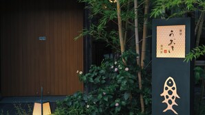 A traditional Japanese building with a wooden door, bamboo plants, and a sign with Japanese characters. - Oyado Uoki (Yugawara)