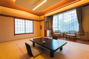 A traditional Japanese room with tatami flooring, a low table, and sliding doors. - Oyado Uoki (Yugawara)