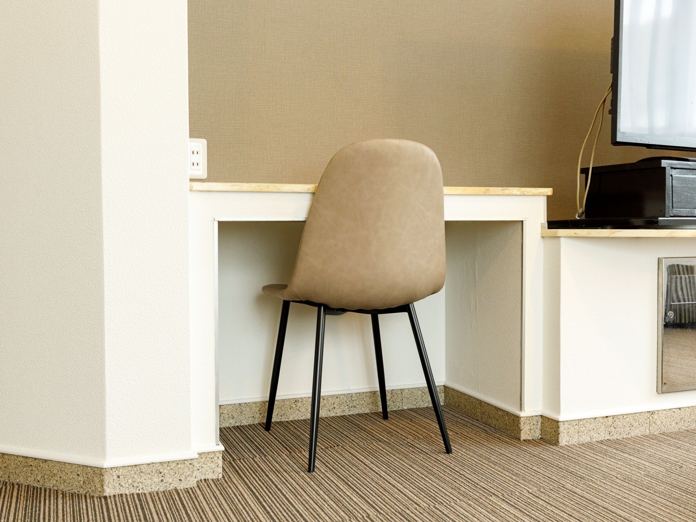 A modern office chair with a high backrest and black legs, positioned at a white desk with a computer monitor.