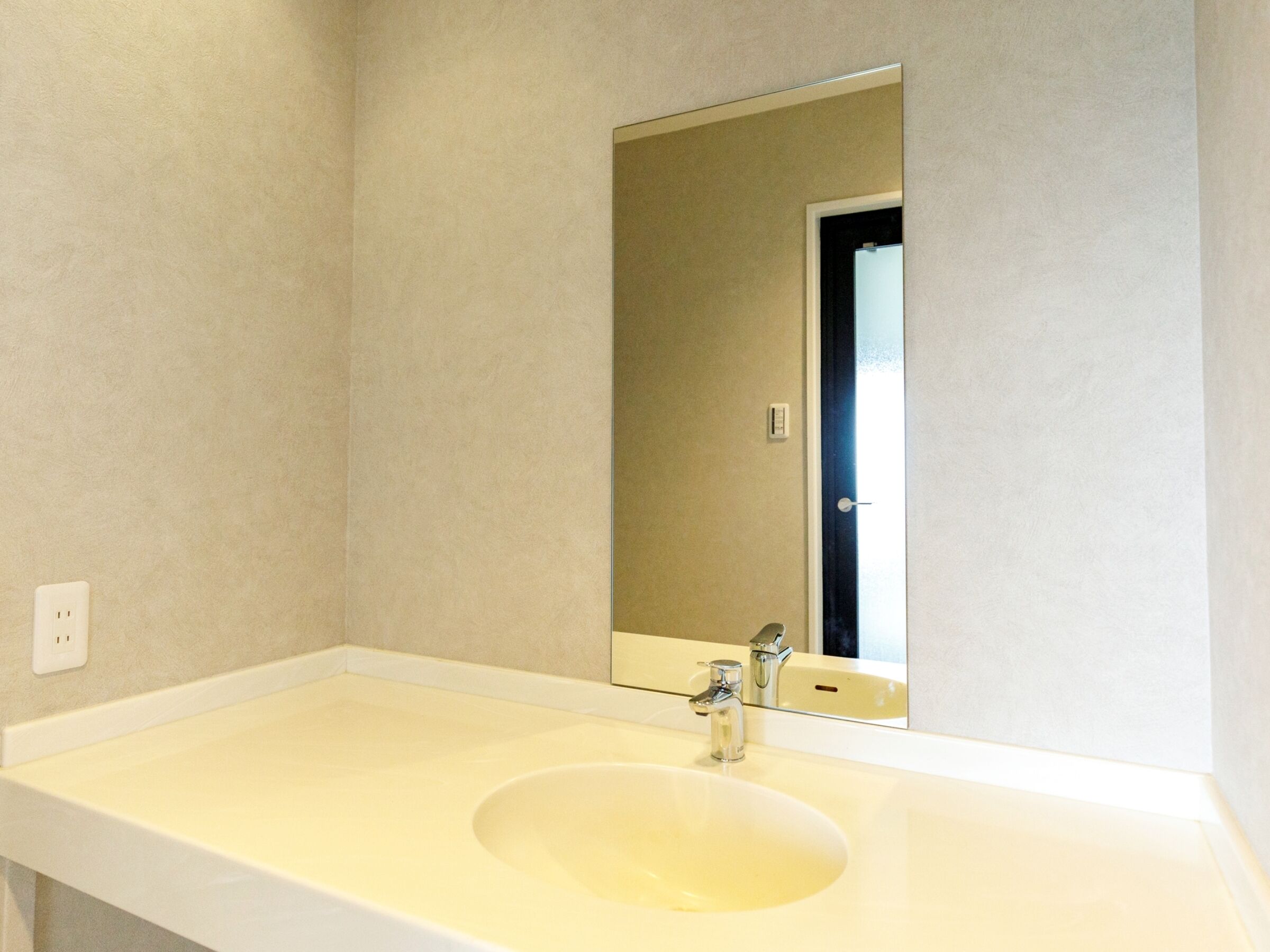 Une salle de bain avec un lavabo blanc, un miroir et une porte.