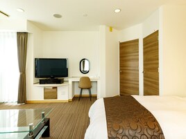 Una habitación de hotel con cama, televisión, escritorio, silla y armario.