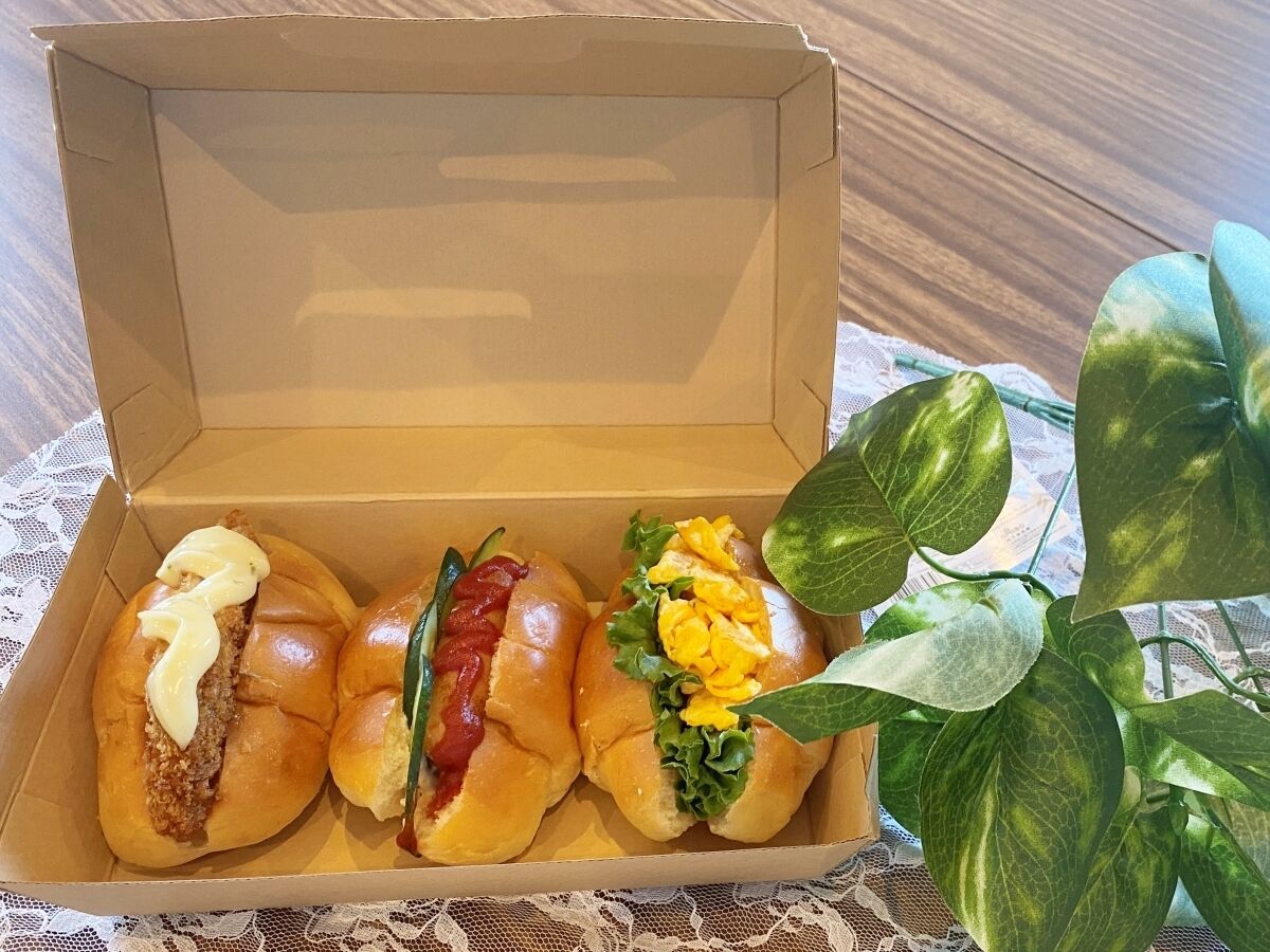 An open cardboard box containing three different types of sandwiches.