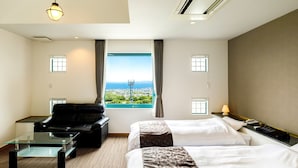 A hotel room with two beds, a sofa, a glass coffee table, and a view of the city and sea. - BEPPU KANKO HOTEL ACE (Beppu)