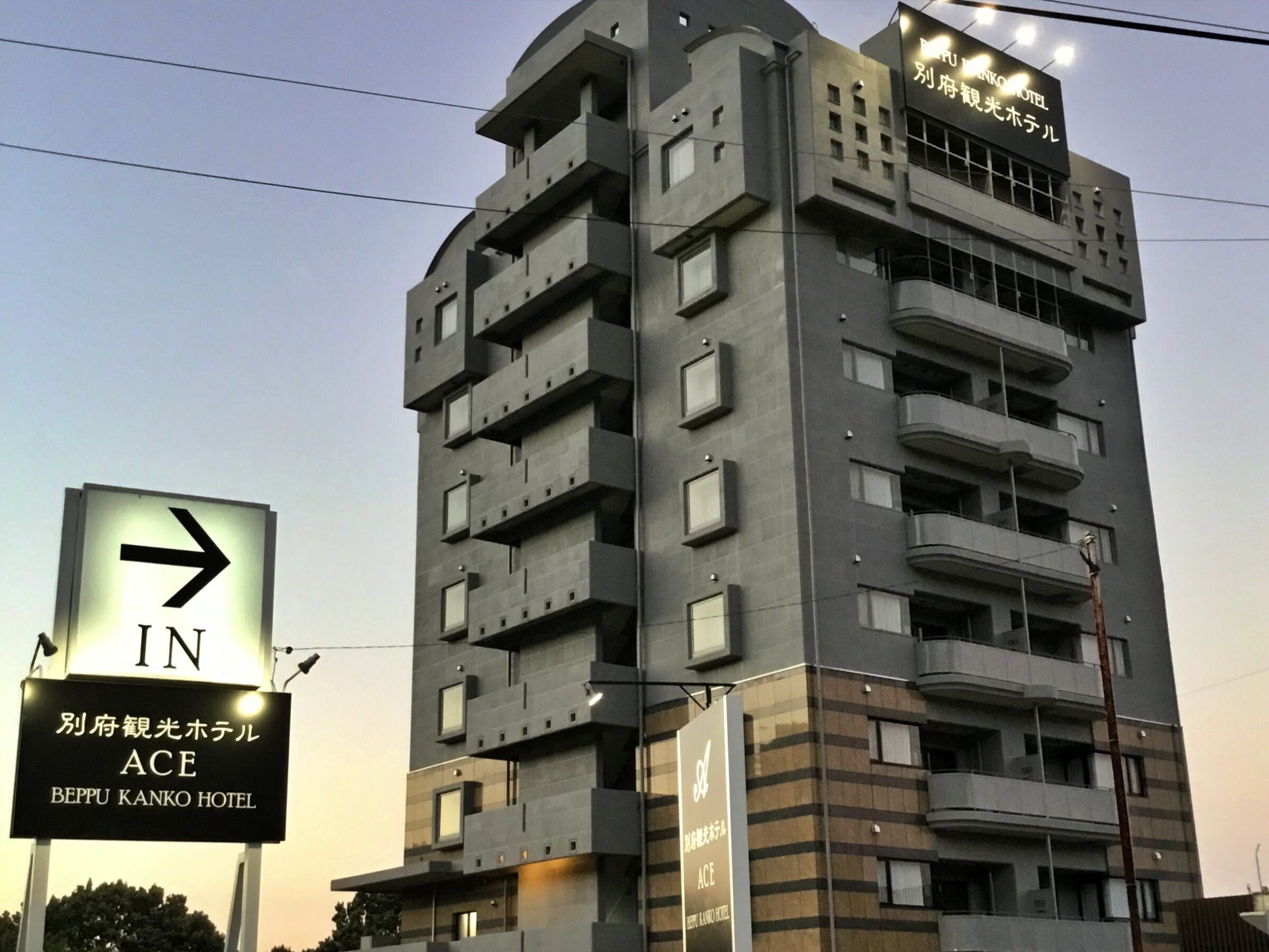 A multi-story hotel with a modern architectural design, featuring balconies and a sign indicating the entrance direction.