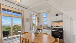 A spacious kitchen with a dining area, large windows, and a view of greenery.