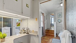 A bathroom with a sink, mirror, towel rack, and a small plant.