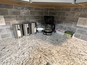 Eine Küche mit Granitarbeitsplatten, Edelstahlgeräten und einer Kaffeemaschine.