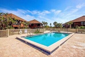 A rectangular swimming pool with a tiled edge, surrounded by a brick patio.