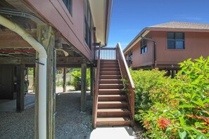 A staircase leading to a building with a balcony, surrounded by greenery and a gravel path. - Enjoy pool views from your Sanibel Island Villa - private beach - pet friendly - Signal Inn 04 (Sanibel)