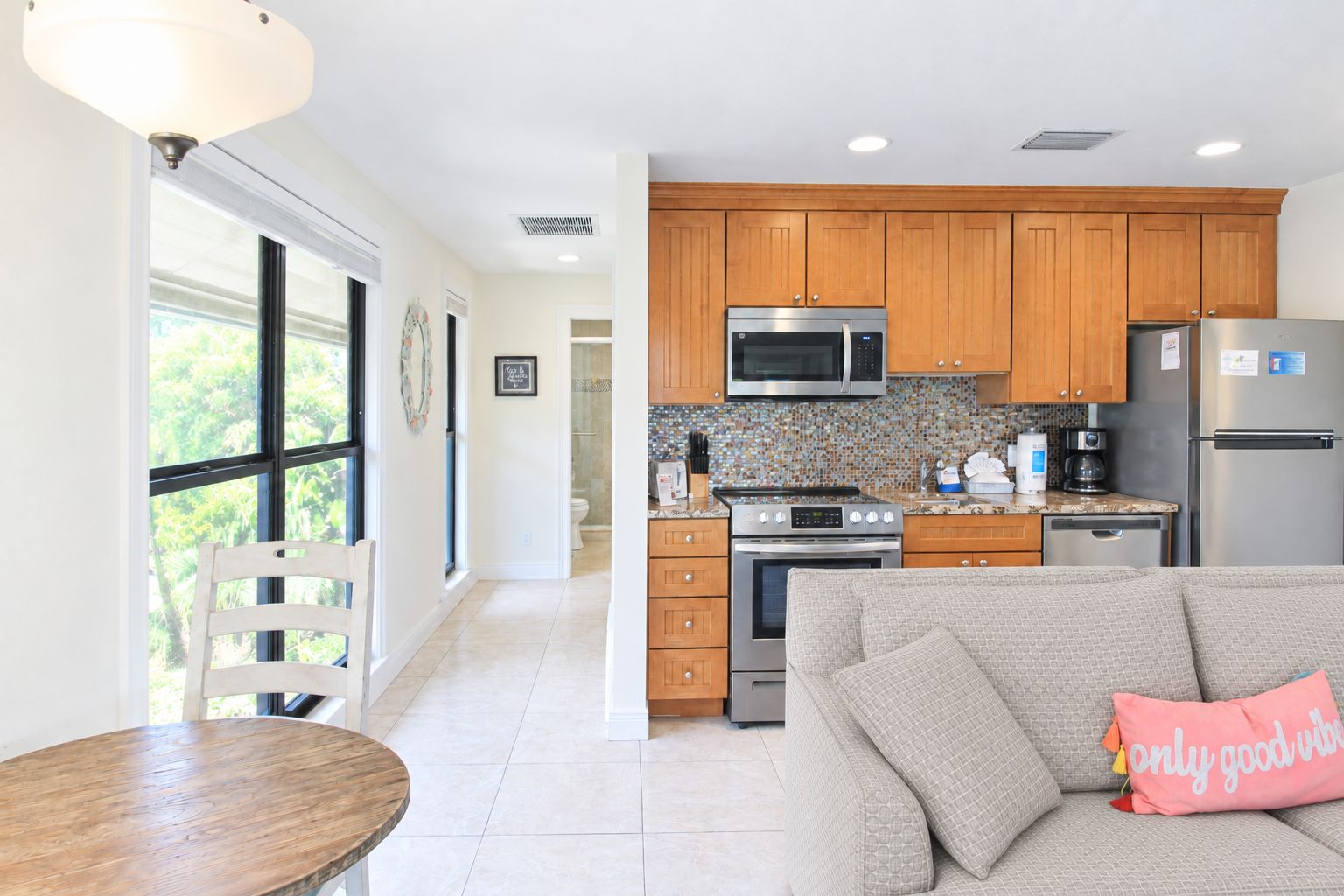 A modern kitchen with wooden cabinets, a stainless steel refrigerator, and a microwave.