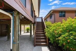 A staircase leading to a building with a wooden deck and a garden with orange flowers.