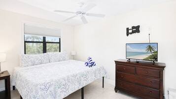 A bedroom with a bed, a nightstand, a dresser, a television, and a ceiling fan.