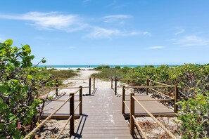 A wooden boardwalk leading to a beach with clear skies.
