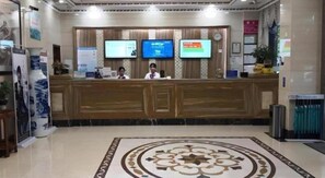 A hotel reception area with a wooden reception desk, three monitors, and a patterned floor. - Greentree Alliance Hotel Foshan Nanhai District Pingzhou Yuqi Street (Foshan)